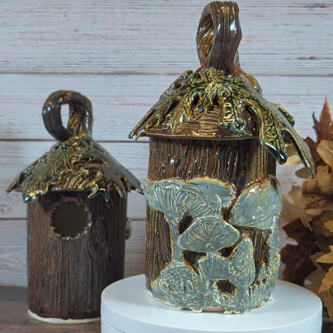 Two birdhouses; both are textured in wood grain and have leaves on the roof of the house. They are both made to look like logs, with mushrooms growing on them. One is facing the cameral while the second one has it's back to the camera to show off the mushrooms.