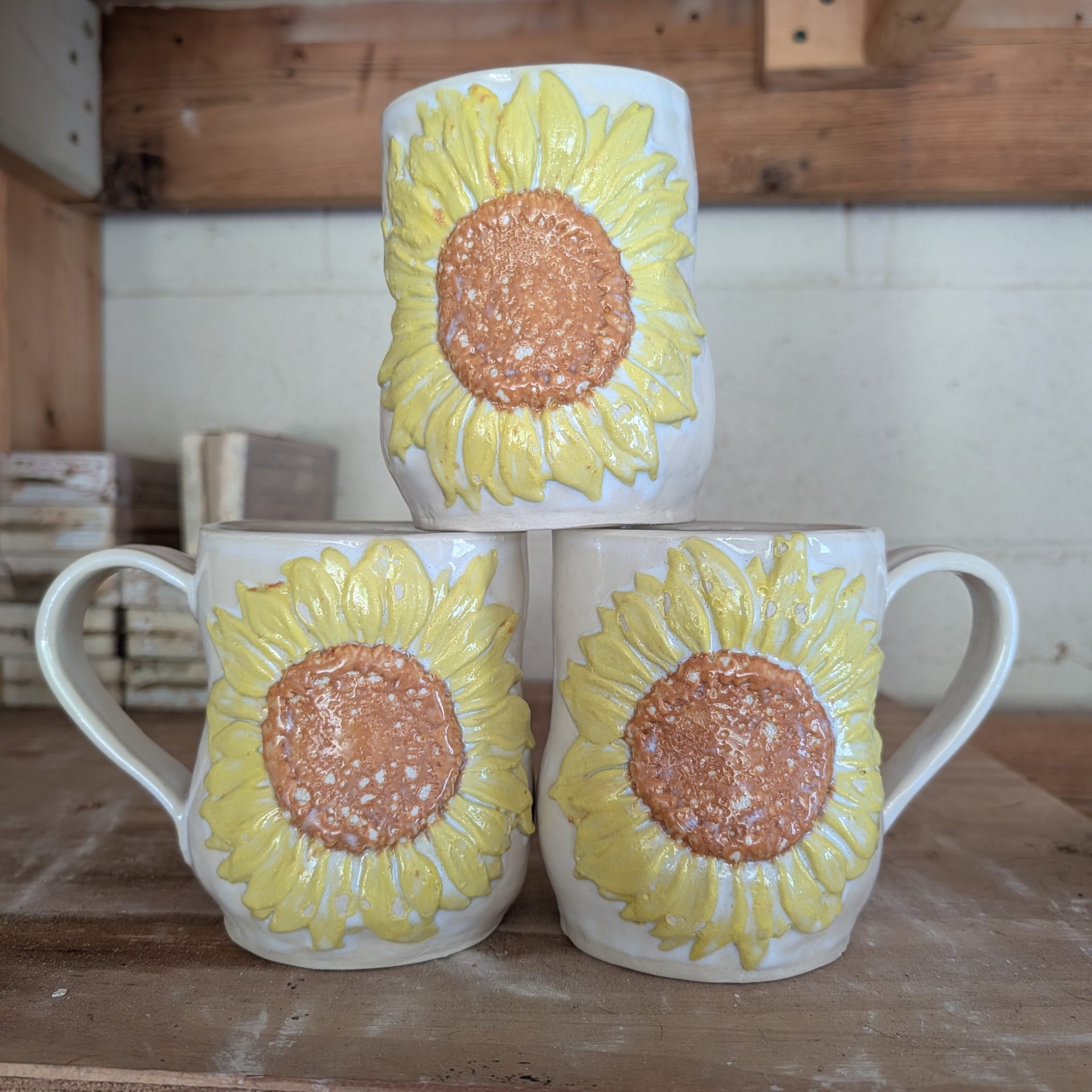 A stack of three white mugs with yellow and brown sunflowers on them