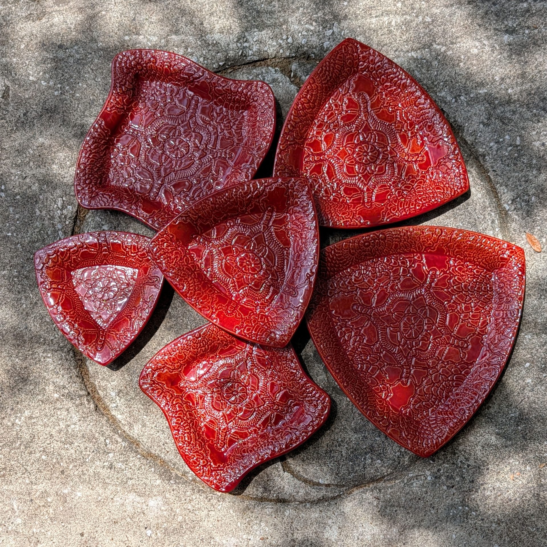 A selection of square and triangular red plates half in shadow on a stone stoop.