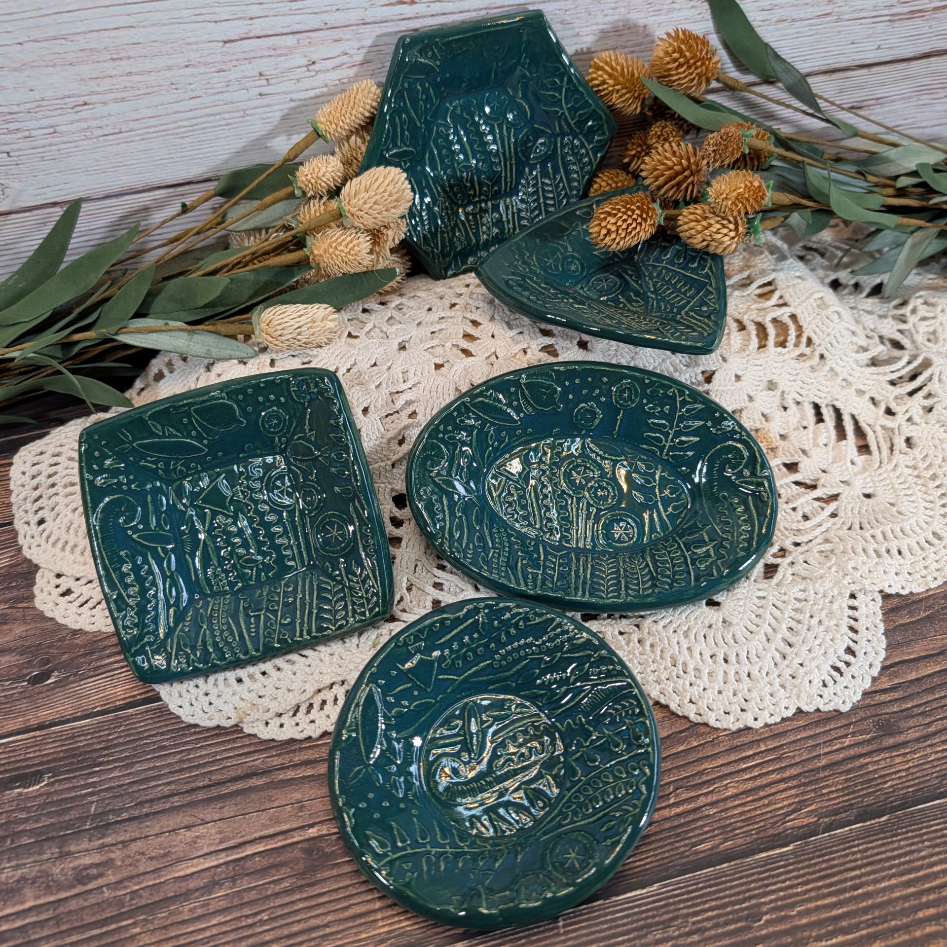 A selection of trinket dishes on a white doily on a wooden surface.